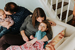 Mid adult couple on sofa with baby son and toddler daughter