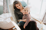 Baby boy sitting on mother's lap, portrait