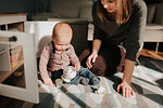 Mother playing with baby son on living room rug