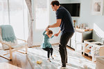 Father playing with toddler daughter on living room rug