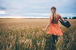 Woman swinging suitcase in wheat field, Edmonton, Canada