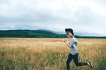 Woman running in wheat field, Edmonton, Canada