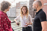 Man and female friends talking, river and buildings in background, Berlin, Germany
