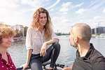 Man and female friends talking, river in background, Berlin, Germany