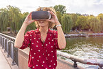 Young woman using VR headset on bridge, river in background, Berlin, Germany