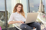 Young woman using laptop on chair outdoors