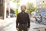 Indian man exploring city, bicycles in background, Berlin, Germany