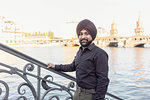 Indian man exploring city, river in background, Berlin, Germany