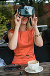 Woman using virtual reality headset in cafe