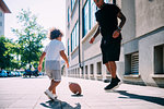 Father and son playing with rugby ball on sidewalk