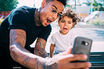 Father and son taking selfie on bench