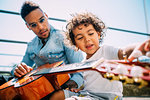 Father teaching son play guitar on stairway