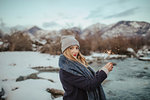 Woman in knitted hat holding sparkler on snow covered riverbank, portrait,  Orta, Piemonte, Italy