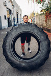 Man with prosthetic leg weight training with giant tyre