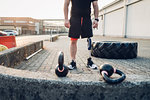 Man with prosthetic leg beside training tyre and kettlebells