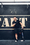 Man with prosthetic leg leaning on wall in gym