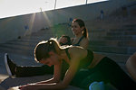 Friends stretching on steps in sports stadium