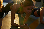 Friends doing plank in sports stadium at sunset