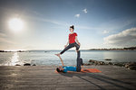 Women practising acro yoga at seaside