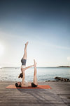 Women practising acro yoga at seaside