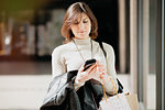 Female shopper using smartphone in front of shop