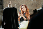 Female shopper taking photograph of top in front of fashion boutique