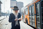 Senior businessman using digital tablet beside bus in city, Milano, Lombardia, Italy