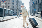 Senior businessman with wheeled luggage in city, Milano, Lombardia, Italy