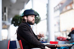 Man in trilby sitting at sidewalk cafe table