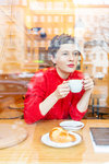 Mid adult woman in cafe drinking coffee looking out, window view