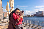 Mother hugging daughter by river, Berlin, Germany