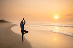 Man practising yoga on beach