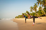 Couple practising yoga on beach