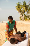 Woman massaging man on beach