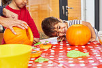 Children carving pumpkin in kitchen