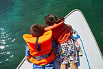 Children looking down into sea water on boat