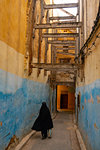 Woman in black traditional dress disappears down a colourful alleyway in the Old City (Medina) of Fez, Morocco, North Africa, Africa