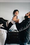 Girl being held up by father in bedroom, portrait