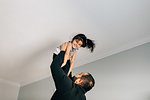 Girl being held up to ceiling by father