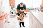 Girl playing in kitchen in front of father and baby brother, portrait