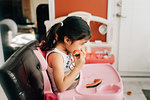 Girl in high chair eating water melon, side view