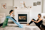 Girl sliding down living room slide, mother watching