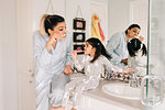 Girl and mother brushing their teeth in bathroom