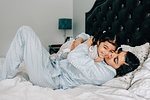 Girl and mother hugging on bed in morning