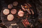 Burgers and sausages cooking on campfire