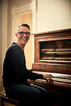 Man grinning and playing piano