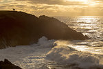 A couple enjoy the view of sunset and crashing waves, Newport, Oregon, United States of America