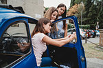 Friends using smartphone beside car