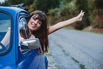 Woman driving, sticking head and arm out of car window