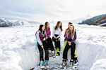 Five teenage girl skiers sitting laughing in snow covered landscape, Tyrol, Styria, Austria